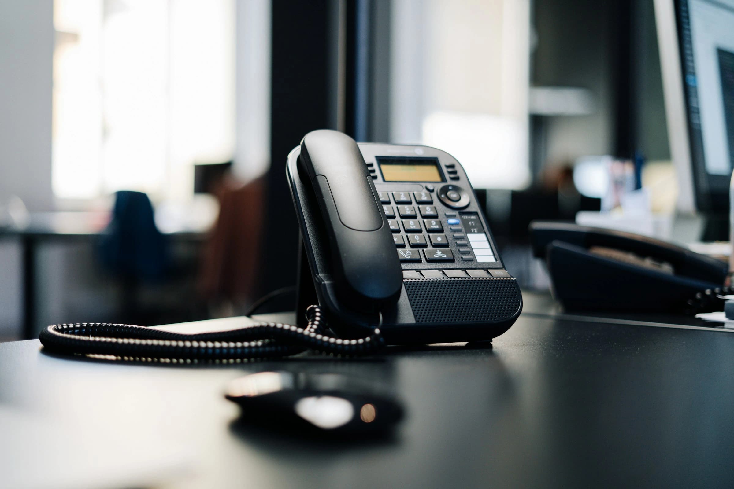 Téléphone IP sur un bureau, open space en arrière-plan